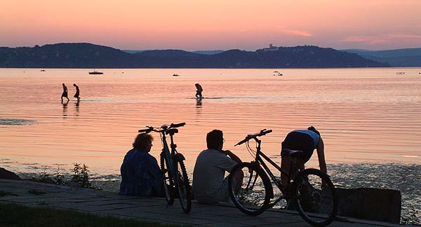 Kerékpárosok pihennek a Balaton partján naplementekor